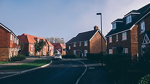 A quiet residential street lined with red-brick houses in Farnham, England.