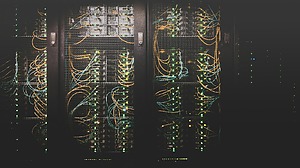 Server racks with network cables and illuminated indicator lights in a dark server room.