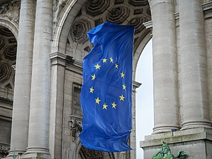 The EU flag hangs beneath an arch in Brussels.
