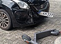 A damaged car and scooter after a collision in an urban setting.