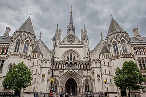 The Royal Courts of Justice in London under a grey, cloudy sky.
