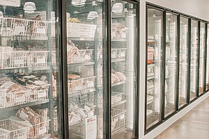 Frozen meats in a retail freezer with transparent doors. 