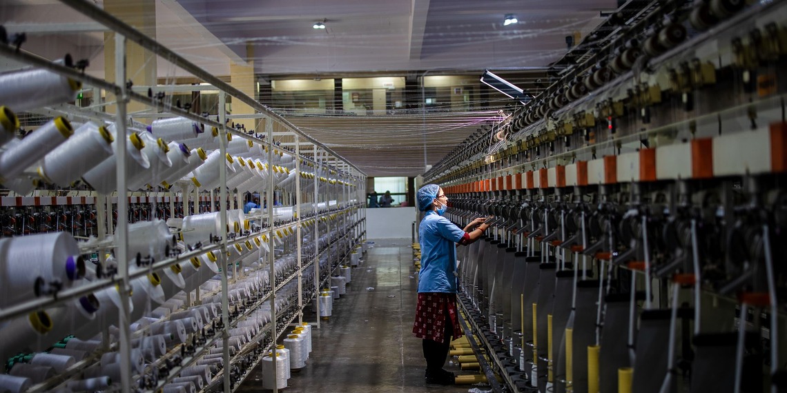 A person stands in between two textile manufacturing machines.
