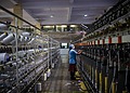 A person stands in between two textile manufacturing machines.