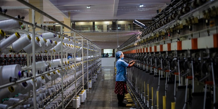 A person stands in between two textile manufacturing machines.