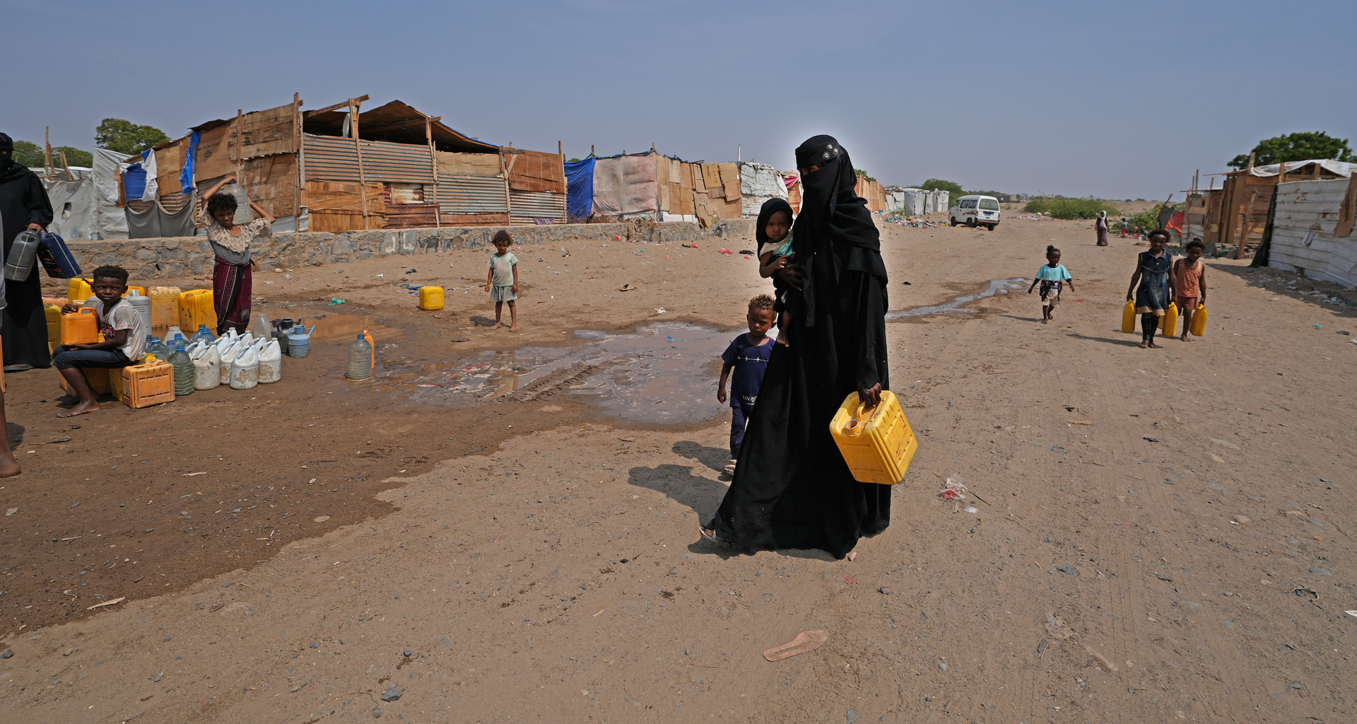 Women and children fill water container to carry back to their shelters Ammar Bin Yasser camp for internally displaced people.