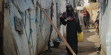 Aisha, a pregnant internally displaced person, going back into her shelter after getting water in Ammar Bin Yasser Camp in Aden, Yemen, Feb. 28, 2022.