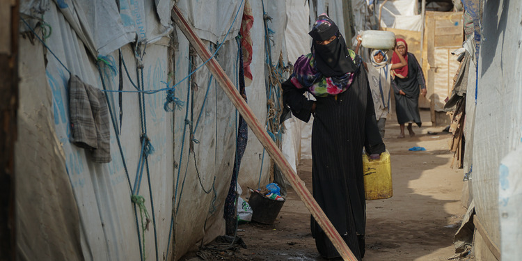 Aisha, a pregnant internally displaced person, going back into her shelter after getting water in Ammar Bin Yasser Camp in Aden, Yemen, Feb. 28, 2022.