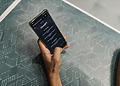 Close-up of a person holding a smartphone displaying the ChatGPT application interface on a patterned table.