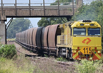 A yellow locomotive pulling coal wagons in New South Wales, Australia.