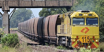 A yellow locomotive pulling coal wagons in New South Wales, Australia.