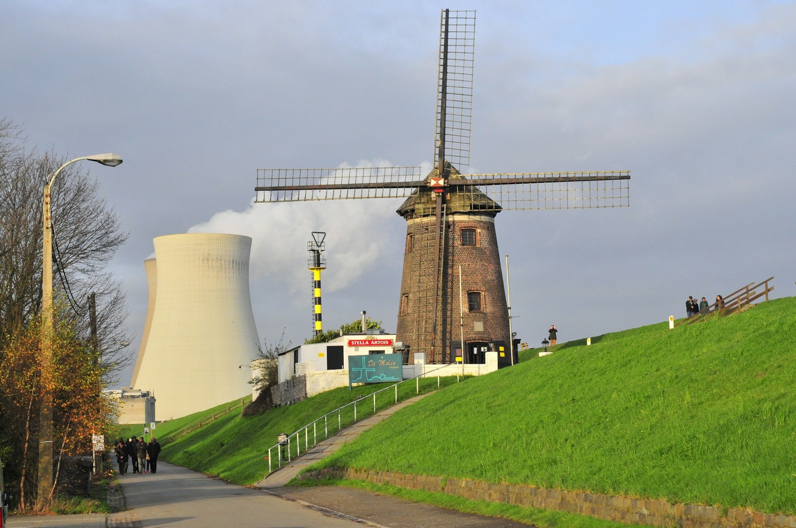An old windmill in front of a nuclear power plant