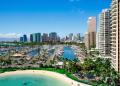 High-rise buildings line a coastal bay beside blue water.