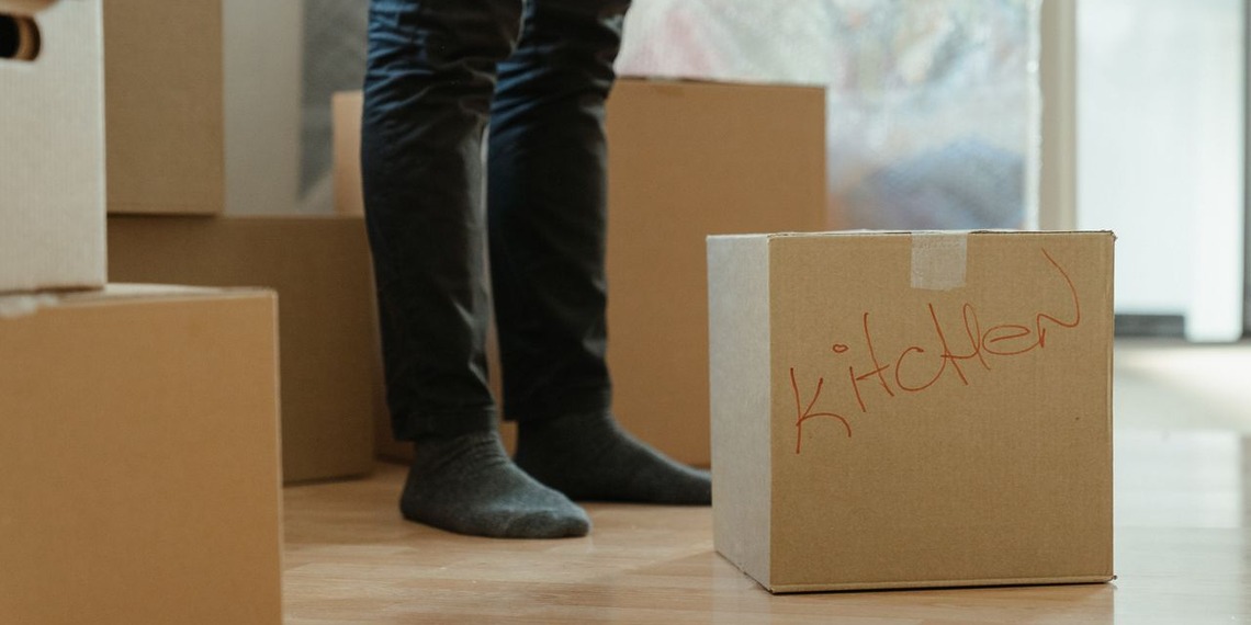 Person standing beside packed cardboard boxes during a home move