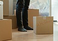 Person standing beside packed cardboard boxes during a home move