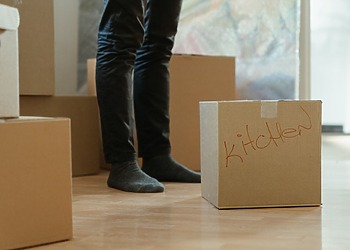Person standing beside packed cardboard boxes during a home move