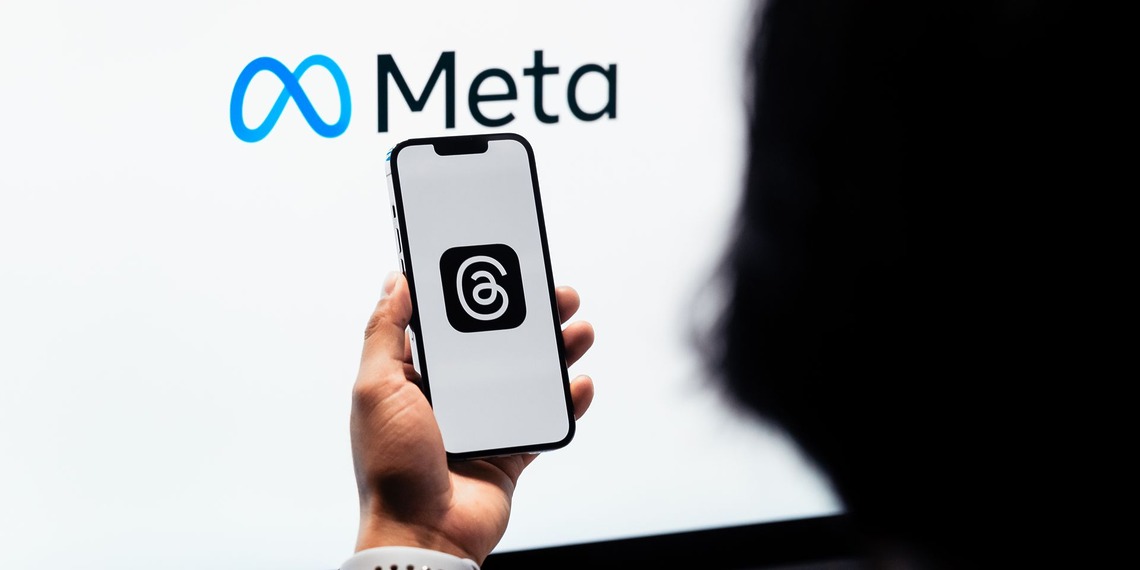 Meta logo displayed on a screen behind a person holding a phone.