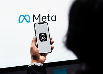 Meta logo displayed on a screen behind a person holding a phone.