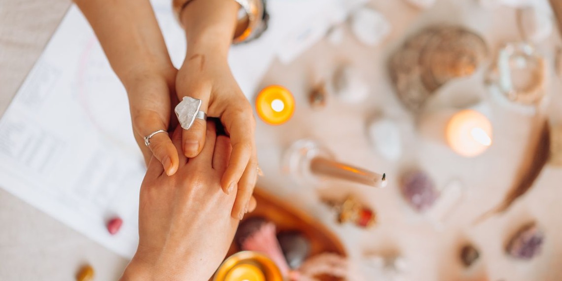 Two people holding hands during a psychic reading with candles