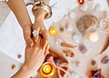 Two people holding hands during a psychic reading with candles