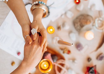 Two people holding hands during a psychic reading with candles