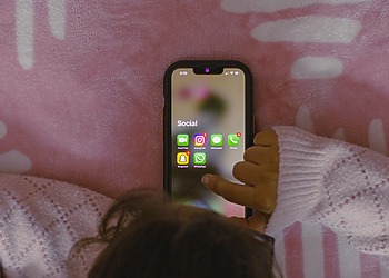 Small child using a smartphone, showing social media apps.