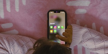 Small child using a smartphone, showing social media apps.