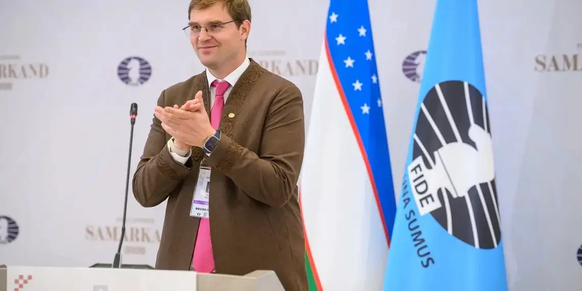 Timur Turlov standing beside the FIDE flag at the 2026 FIDE Congress in Samarkand