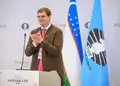 Timur Turlov standing beside the FIDE flag at the 2026 FIDE Congress in Samarkand